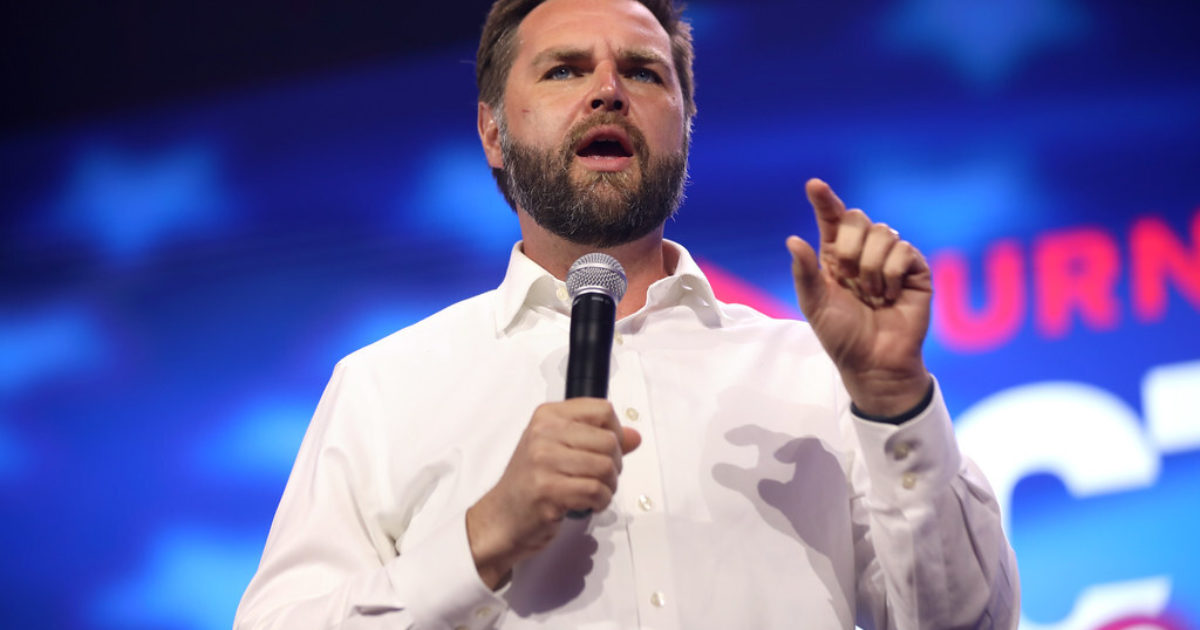 JD Vance speaking with a microphone and gesturing with his hand