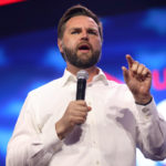 JD Vance speaking with a microphone and gesturing with his hand