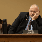 Wisconsin Republican Jesse James sitting behind his nameplate with his face resting in his palm