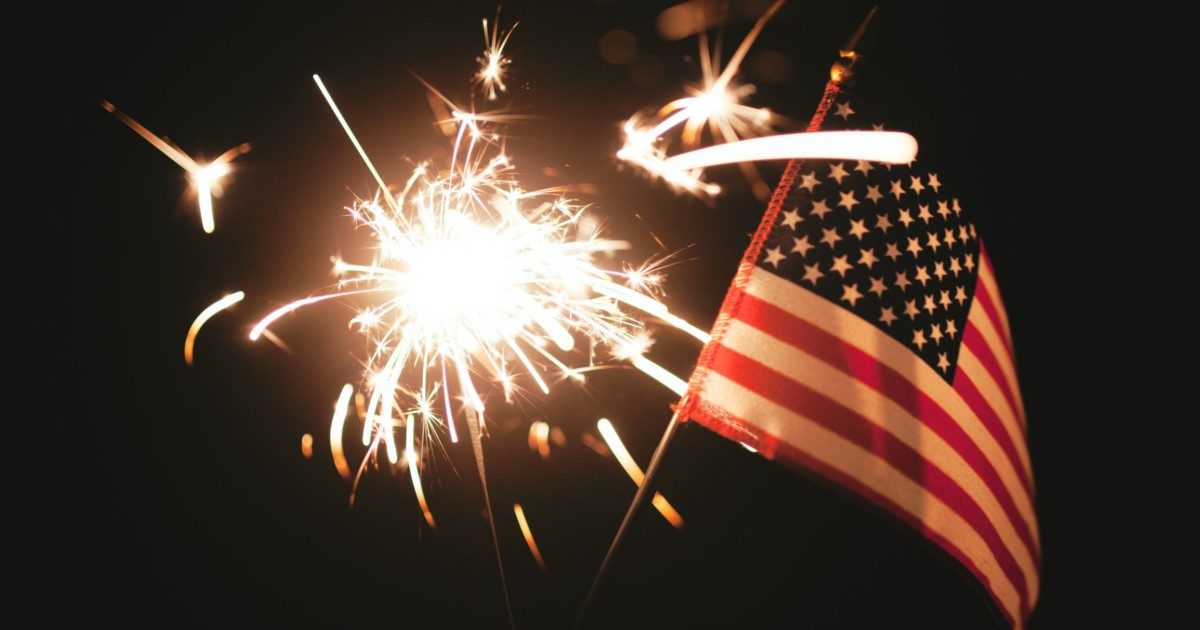 hand holding sparkler and small flag