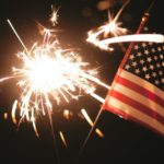 hand holding sparkler and small flag