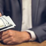 Rich businessman holding and giving US dollar money in dark private room for the invesment - bribery and corruption concept, panoramic banner