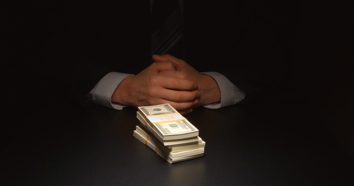 Businessman sits near a heap money on a table