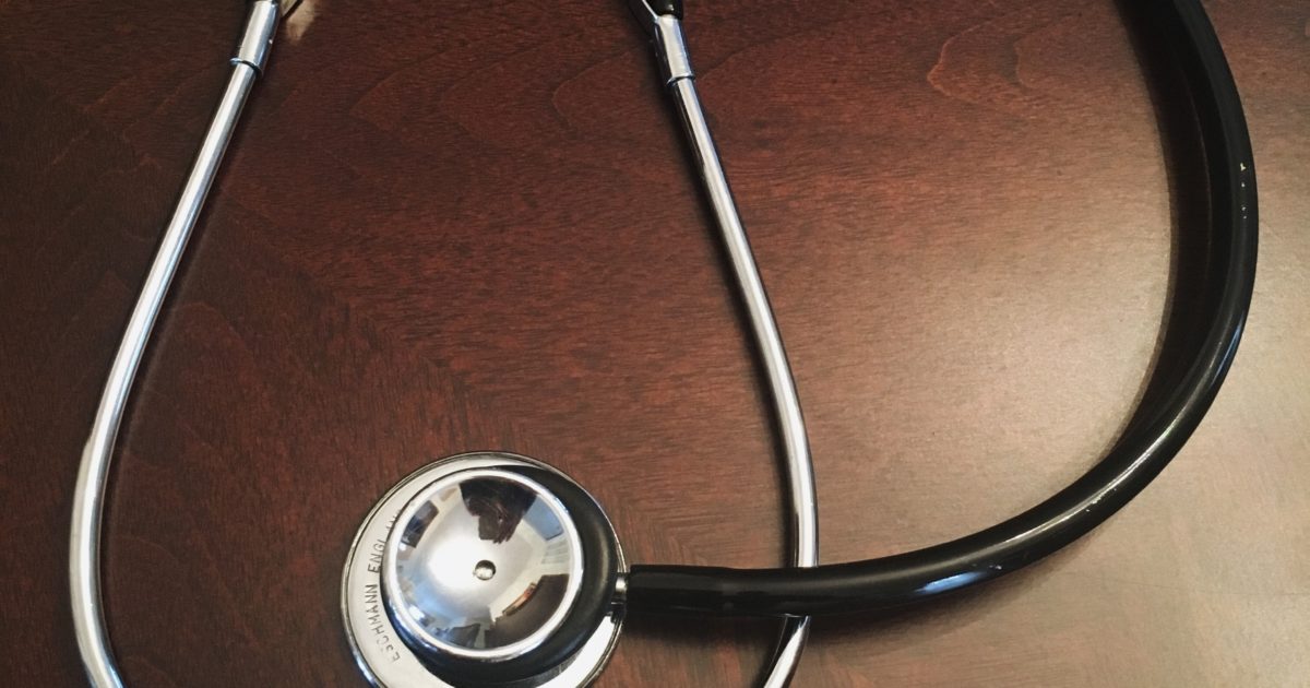 stethoscope and pills on wooden desk